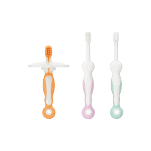 Combi Teteo Steps 1 to 3 training toothbrushes in orange, purple and green, with a detachable shield on the Step 1 brush.